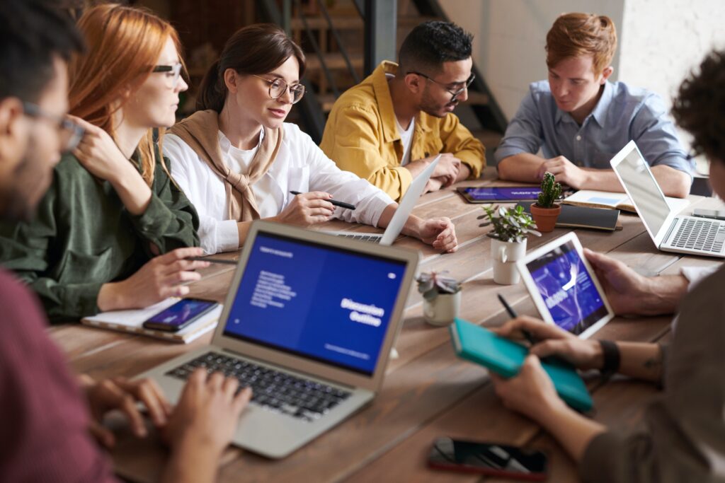 Equipo de trabajo reunido alrededor de una mesa con portátiles